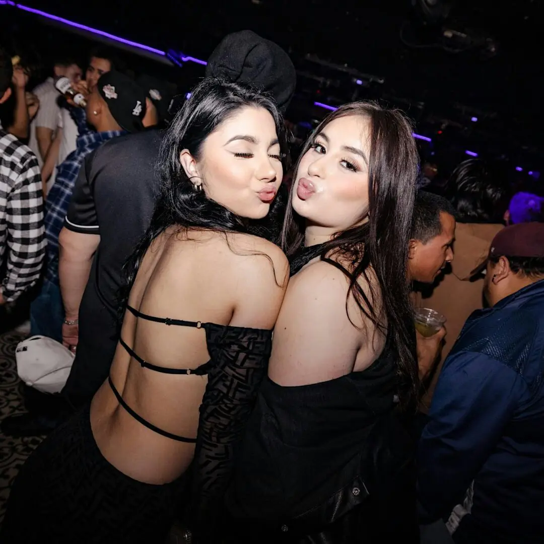 Two women puckering faces in crowded nightclub